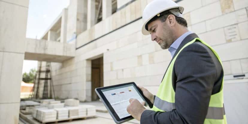 Chef de chantier utilisant une tablette pour le suivi de projet de pierre sur un site de construction en pierre naturelle