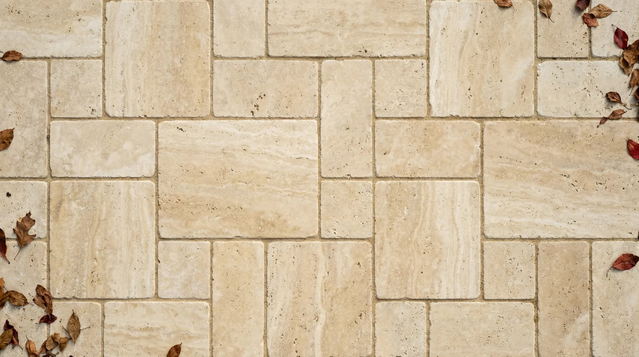 Top-down view of French pattern Versailles layout with four sizes of tumbled travertine pavers showing natural beige color variation