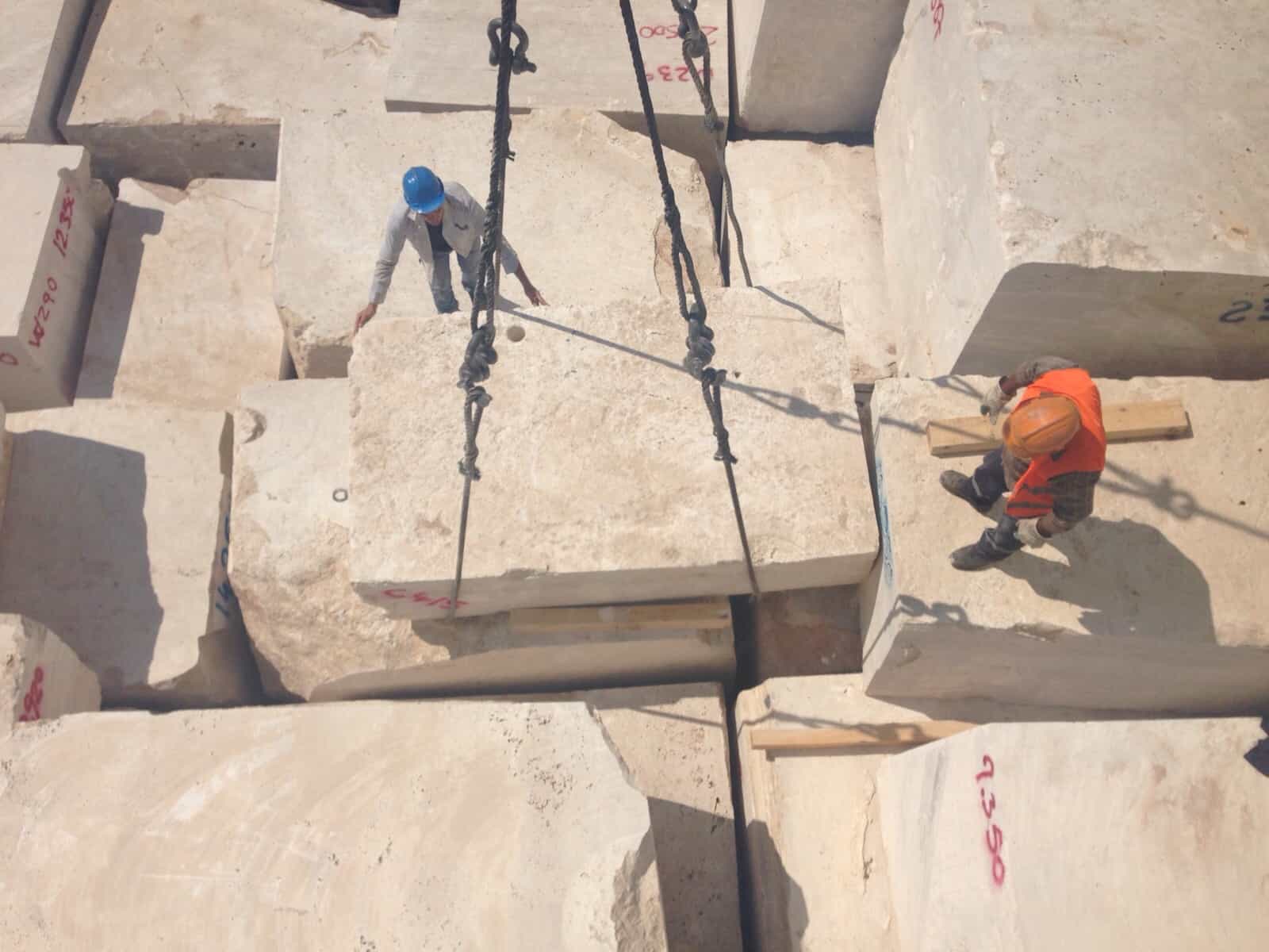 A crane hoists large blocks of marble, showcasing the strength and precision of heavy machinery in construction.