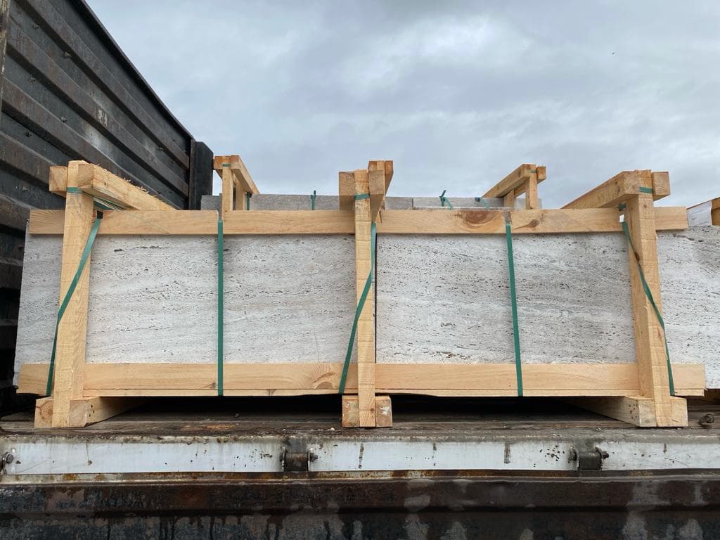 Vein-Cut Silver Travertine tiles secured with wooden crate, showing grey veined pattern and sandblasted finish Vein-Cut Silver Travertine tiles secured with wooden crate, showing grey veined pattern and sandblasted finish